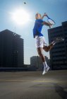 Jugador de tenis saltando en la pista de la azotea - foto de stock