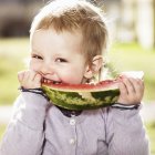 Тоддлер ест арбуз на открытом воздухе — стоковое фото