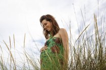 Pregnant woman standing in field — Stock Photo