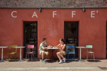 Pareja sentada fuera de la cafetería, Florencia, Toscana, Italia - foto de stock