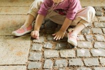Girl drawing with chalk on cobblestone — Stock Photo