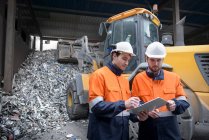 Arbeiter inspizieren Papierkram in Recyclinganlage vor Aluminiumschrott — Stockfoto