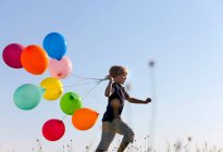 Хлопчик з різнокольоровими кульками в траві — стокове фото
