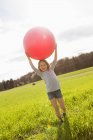 Girl carrying bouncy ball in field — Stock Photo
