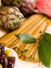 Artichokes, pasta and olives on table — Stock Photo