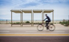Movimiento borroso del ciclista en bicicleta a lo largo de la carretera costera, Cagliari, Italia - foto de stock