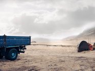 Camion blu e scavatrice in campo asciutto con cielo nuvoloso — Foto stock