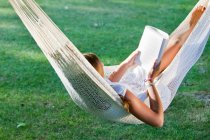 Girl reading book in a hammock — Stock Photo