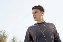 Молодий чоловік на відкритому повітрі, одягнений у спортивний одяг та навушники — стокове фото