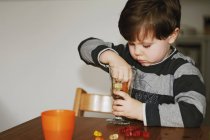 Хлопчик грає з цукерками за столом — стокове фото