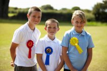 Children wearing ribbons in field, focus on foreground — Stock Photo