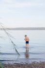Rapaz vadear na praia rochosa — Fotografia de Stock