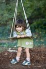 Little girl playing on wood swing — Stock Photo