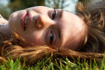 Gros plan de la fille couchée dans l'herbe — Photo de stock