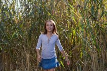 Улыбающаяся девушка идет по пшеничному полю — стоковое фото
