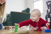Baby girl playing with building blocks on living room floor — Stock Photo