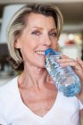 Senior femme eau potable — Photo de stock