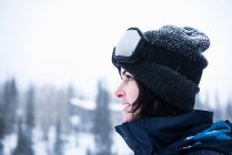 Portrait d'une jeune femme portant des lunettes de ski regardant la neige, station de ski de Brighton en dehors de Salt Lake City, Utah, États-Unis — Photo de stock