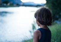 Вид сзади на мальчика у реки, отводящего взгляд — стоковое фото