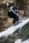 Snowboarder che salta sul pendio roccioso — Foto stock
