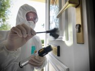Forensic scientist brushing front door for fingerprints at crime scene — Stock Photo