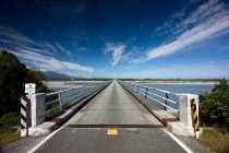 Ponte che si estende sul fiume rurale con cielo blu — Foto stock