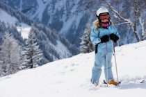 Девушка с лыжами стоит на снегу — стоковое фото