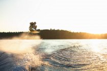 Wakeboarder sautant dans les airs au coucher du soleil — Photo de stock