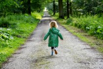 Rückansicht von Mädchen, das tagsüber im Wald läuft — Stockfoto
