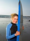 Retrato de uma surfista feminina com prancha de surf na praia — Fotografia de Stock