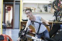 Frau in Fahrradwerkstatt überprüft Pedal am Liegerad — Stockfoto