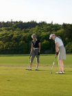 Dos mujeres en el golf verde - foto de stock