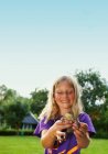 Дівчина тримає жабу на задньому дворі, фокус на передньому плані — стокове фото