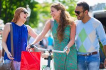 Amigos rindo, mulheres empurrando bicicleta — Fotografia de Stock