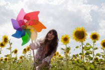 Frau hält Windmühle im Sonnenblumenfeld — Stockfoto
