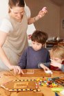 Family decorating gingerbread house — Stock Photo