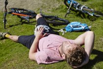 Велосипедист лежит на траве на велосипеде — стоковое фото