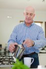 Older man pouring cup of coffee — Stock Photo