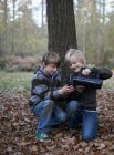 Мальчики наливают горячий напиток из фляжки в осенний лес — стоковое фото