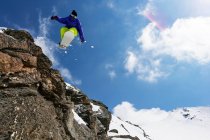 Сноубордист стрибає на скелястому схилі — стокове фото