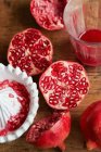 Halved pomegranates with juicer and juice in glass — Stock Photo