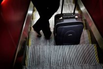 Frau steht mit Gepäck auf Rolltreppe — Stockfoto