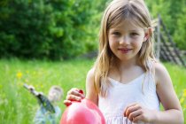 Close portrait of young girl holding red balloon — Stock Photo