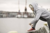 Läuferin bindet Trainer-Schnürsenkel an Hafenseite — Stockfoto