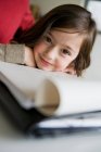 Усміхнена дівчина робить домашнє завдання за столом — стокове фото