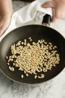Шеф-кухар тримає сковороду з підсмаженими кедровими горіхами — стокове фото