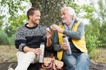 Father and adult son drinking coffee from flask — Stock Photo