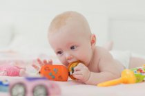 Baby chewing on rattle on blanket — Stock Photo