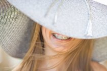 Sorridente ragazza con l'apparecchio che indossa il cappello da sole — Foto stock
