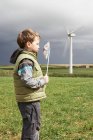 Boy blowing windmill on a wind farm — Stock Photo